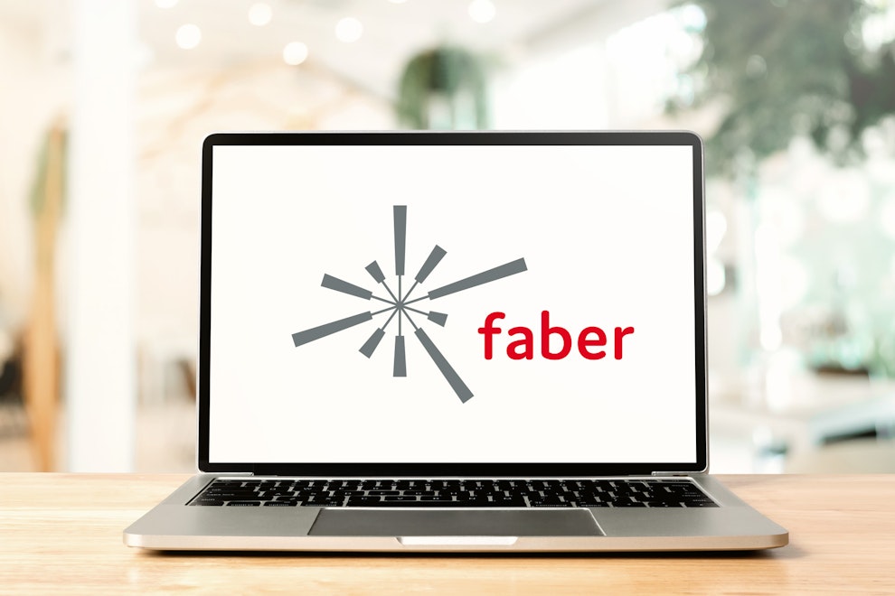 Opened laptop on wooden table with Faber logo on display