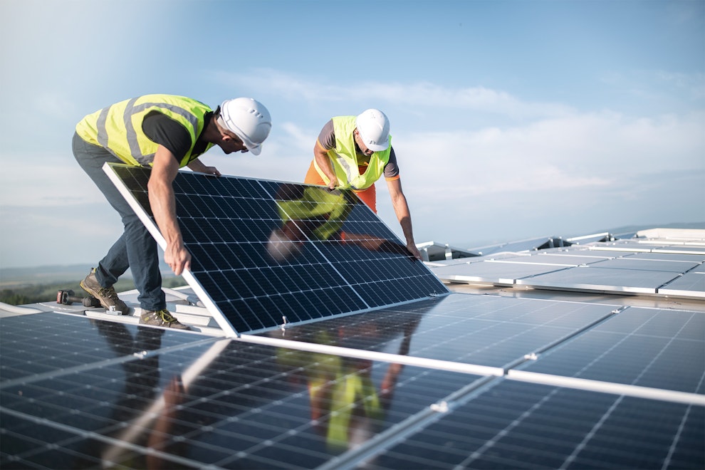 Zwei Ingenieure installieren Sonnenkollektoren auf dem Dach